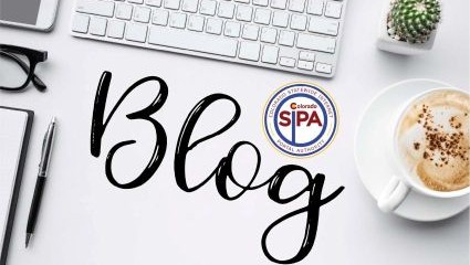 Keyboard, smartphone, coffee, and pen and paper on a desk ready to read SIPA's blog